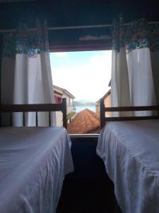 two beds in a bedroom with a view of the ocean at hostel Boa Onda Trindade in Paraty