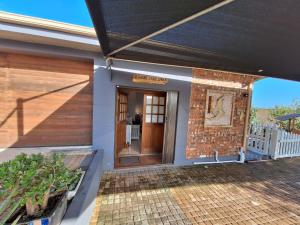 a front door of a house with a brick wall at Mooisig oornagverblyf in Mossel Bay