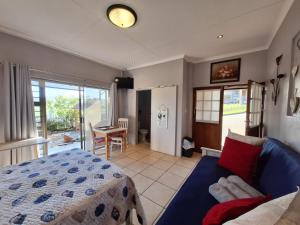 a bedroom with a bed and a couch and a table at Mooisig oornagverblyf in Mossel Bay