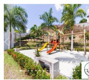 a playground with a slide in a park with palm trees at Apartamento Citadela Di Sole Santa fe De Antioquia in Santa Fe de Antioquia