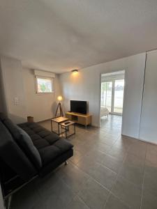 un soggiorno con un divano e una televisione di Garden space - T4 - Airport - Garden - Tram a Blagnac
