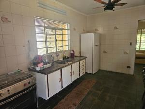 a kitchen with a white refrigerator and a sink at Chácara Paraíso Country House Events in Bauru