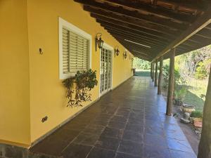 a porch of a house with a yellow wall at Chácara Paraíso Country House Events in Bauru