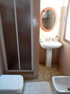 Un baño con lavabo, inodoro y espejo. en I Fenicotteri Baia Caddinas, en Golfo Aranci 13 fotos más
