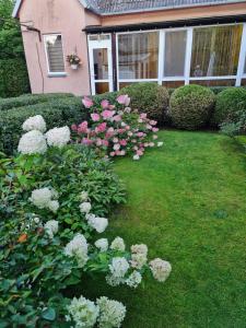 a garden with pink and white flowers in front of a house at Viešnagė Palangoje pas J&I in Palanga +2 photos