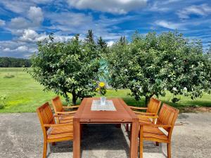 a wooden table with two chairs and two trees at Hof zum alten Birnbaum in Friedland