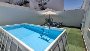a swimming pool with a chair and an umbrella at Casa Yerbabuena in La Puebla de Cazalla