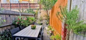 a patio with a wooden table and some plants at Double Bed at Cozy Hailsham in London