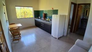 a kitchen with a white refrigerator and a table at Chalé de Pedestre in São Gonçalo do Rio das Pedras +9 photos