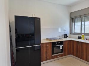 a kitchen with a black refrigerator and wooden cabinets at אחוזת מעלות in Ma'alot Tarshiha