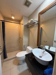 a bathroom with a sink and a toilet and a mirror at Executive Suites Bellagio Golf View Residences in Manila