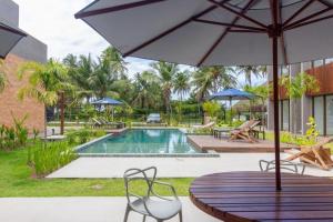 a table with an umbrella next to a swimming pool at Apartamento Luxo em Japaratinga in Japaratinga