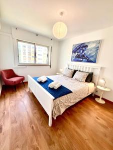 a bedroom with a white bed and a red chair at Retiro dos Poetas, cozy and spacious in Oeiras