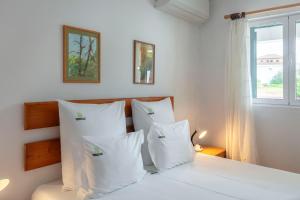 a white bedroom with a bed with white pillows at Casas do Porto - Azalea and Hortênsia in Mosteiros