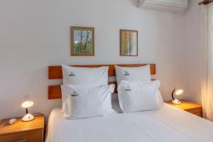 a bedroom with a bed with white sheets and pillows at Casas do Porto - Azalea and Hortênsia in Mosteiros