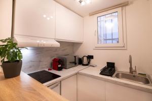 a kitchen with white cabinets and a sink and a window at Studio Place Masséna in Nice