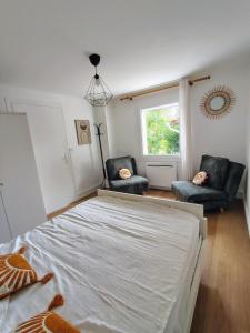 a bedroom with two chairs and a bed and a window at Appartement calme avec jardin in Saint-Ambreuil