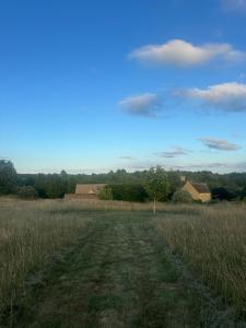 a field with a dirt road in the middle at Stunning Cotswolds guest house in Chadlington +5 photos