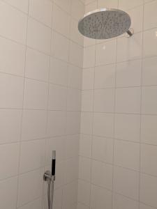 a shower with a white tiled wall and a light at Herman in Bruges