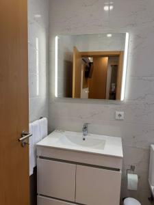 a white bathroom with a sink and a mirror at Vivenda Por do Sol in Couço