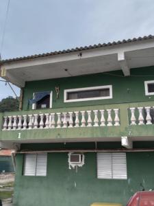 a green building with a balcony on the side of it at Kit Perequê Guarujá in Bertioga