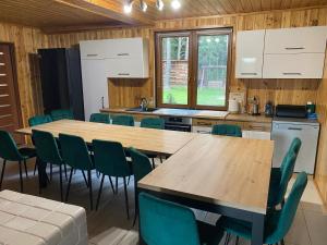 eine Küche mit Holztischen und grünen Stühlen in der Unterkunft Leśny Zakątek in Augustów