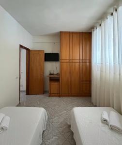 a bedroom with two beds and a desk and wooden cabinets at Graci Apartments in Sarandë