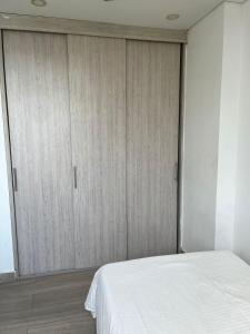 a bedroom with a white bed and wooden cabinets at HABITACIÓN CENTRAL EN CASA FAMILIAR, A 10 minutos de la playa in Santa Marta
