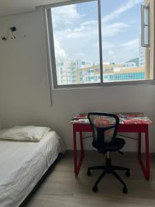 a bedroom with a desk and a chair in front of a window at HABITACIÓN CENTRAL EN CASA FAMILIAR, A 10 minutos de la playa in Santa Marta
