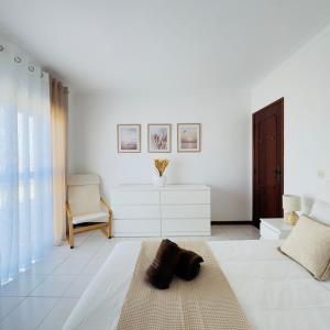 a white living room with a couch and a chair at Recanto das Areias - 2-bedroom apartment 5 minutes from the beach in Torreira