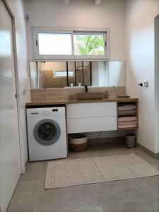 a bathroom with a washing machine and a sink at La petite villa in Le Gosier