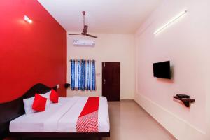 カンニヤークマリにあるHotel O Aljeminの赤い壁のベッド1台が備わる客室です。 +39枚の写真