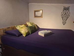 Schlafzimmer mit einem Bett mit lila Bettwäsche und Kissen in der Unterkunft Casa Vista Baepi - Estilo Boho, Mais Streaming a 1,5km da Balsa in Ilhabela