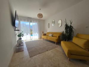 a living room with two yellow couches and a television at Domaine U Filanciu - Centru di Corsica in Moltifao