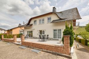 a house with a brick retaining wall and a patio at Gästehaus Binz-Meyer Fewo Paulsberg in Lieser