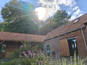 a brick house with the sun shining through the trees at De kleine Bossenare in Maarkedal