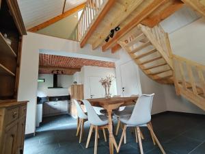a dining room with a wooden table and white chairs at De kleine Bossenare in Maarkedal