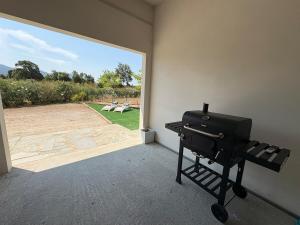 a grill in a room with a view of a patio at Bas de villa 80m2 2 chambres secteur Ajaccio in Tavaco +3 photos