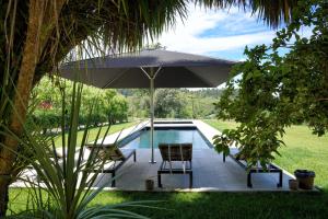 a pool with an umbrella and two chairs and a table at Casa de Docim in Fafe