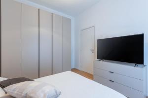 a white bedroom with a tv on a white dresser at Dimora delle Vittorie - Vaticano in Rome