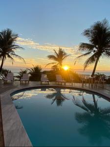 ナタールにあるAtlântico Flat 104 e 116の夕日を背景にしたプール
