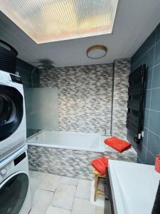 a bathroom with a tub and a washing machine at Gîte du Phare in Grand-Fort-Philippe