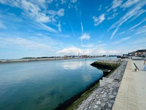 a body of water with a blue sky and clouds at Gîte du Phare in Grand-Fort-Philippe