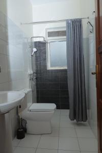 a bathroom with a toilet and a sink and a window at Lake Sight Uganda in Kampala