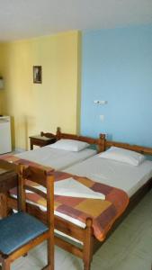 een slaapkamer met 2 bedden en een stoel. bij Green Hill Seaside Studios in Kokkari
