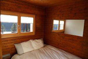 a bedroom with two windows and a bed in it at Appartement sous les combles Sony 29 in Grimentz