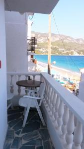 een balkon met een tafel en uitzicht op het strand bij Green Hill Seaside Studios in Kokkari
