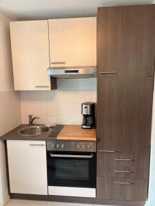 eine kleine Küche mit Herd und Spüle in der Unterkunft Waldzeit Braunlage - WLAN - Parkplatz - Terrasse - ebenerdig in Braunlage