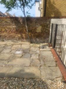 a brick wall with a tree next to a sidewalk at Seaview Charm Herne Bay in Herne Bay