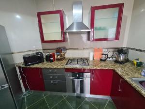 a kitchen with red cabinets and a stove top oven at Apparemment PIED dans l'eau CHOTT MARIEM in Chott Meriem